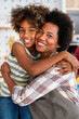 © NDABCREATIVITY - African american woman hugging her smiling teen daughter. Family love single parent child concept