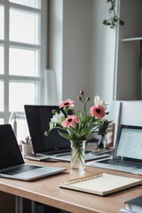 Poster - Beautiful workspace with flowers on a wooden table surrounded by laptops and stationery during daytime