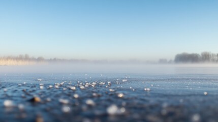 Poster - Frozen lake surface with fog and distant trees under a clear blue sky.