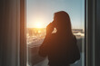 © M-Production - Silhouette of a woman talking on the phone by the office window.