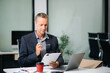 © laddawan - businessman in an office with a laptop, tablet, and notes. Ideal for business, finance, accounting