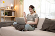 © NINENII - Happy woman having fun doing video call using mobile phone sitting on sofa.