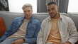 © Krakenimages.com - Men sitting on a couch in a cozy apartment living room, showcasing friendship and a relaxed relationship atmosphere indoors.