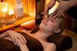 © InfiniteFlow - Caucasian woman enjoying relaxing anti-stress head massage and pampering facial beauty skin recreation leisure in warm candle lighting ambient salon spa in luxury resort or hotel. Quiescent