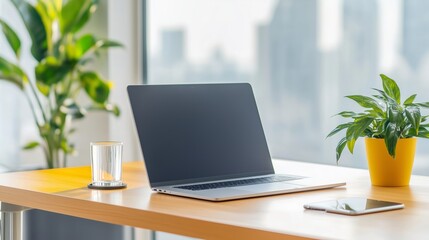 Poster - Stylish workspace with laptop, plant, and glass on a wooden table in a bright office environment