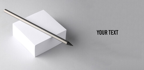Stack of white blank square memo papers with pencil on gray background. Your text, copy space for information