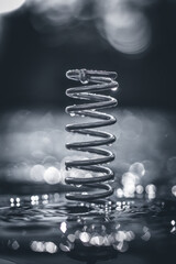 Poster - Elegant Silver Spiral Spring Reflected in Glossy Water with Bokeh Lights