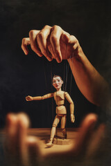 Poster - Human Hand Manipulating a Puppet, Symbolizing Control and Influence with Dramatic Lighting