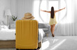 © Pixel-Shot - Female tourist opening curtains in hotel room, back view