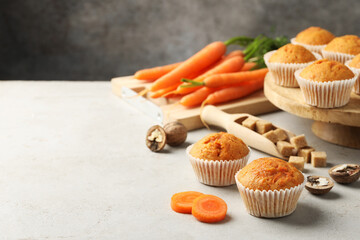 Wall Mural - tasty carrot muffins, fresh vegetables, sugar and walnuts on light grey table, closeup. space for te