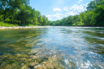 Aufkleber - serene river flows smoothly under bright blue sky, surrounded by lush green trees and rocky shoreline, creating peaceful natural scene