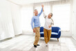 © artitwpd - Happy Asian senior couple dancing together in a bright living room, enjoying an active and joyful lifestyle. Promotes healthy aging, wellness, and the importance of staying active in retirement.