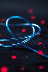 Poster - Colorful blue wire arranged in an artistic formation on a dark background with scattered red dots