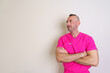 © Javier - Confident male nurse in pink scrubs standing with crossed arms against soft background