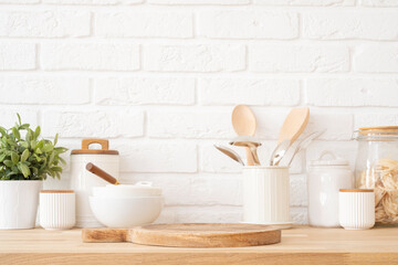 Wall Mural - table top with dish podium board on background of white brick wall and kitchen utensils