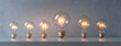 © FEEZAN ALI - 5 light bulbs of different sizes, one bulb is lit up and the other four are off