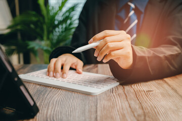 Poster - Professional Man Using Digital Tablet and Keyboard in Modern Office with Green Plant Background, Business concept