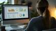 © xuxu - Female data analyst analyzing data using charts on computer screen. Freelancer working from home reviewing financial data on computer screens. Report tables and charts. Back view.
