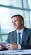 © Exnoi - Thoughtful businessman in a modern office using a tablet device