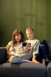© MexChriss - Brother and sister watching videos on smartphone while relaxing on sofa