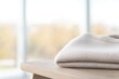 © Andrei - close-up of single folded sweater in soft wool sitting on rustic wooden table surrounded by diffused morning sunlight