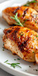 © Purple_Lamp - Close up of seasoned grilled chicken breast with rosemary garnish on a white plate