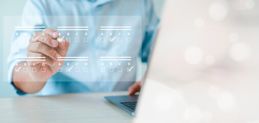assessment survey online. Businessman with evaluating questionnaire on online laptop computer. choose correct answer in test, questions test, online exam, quiz knowledge, filling out an survey form.