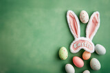 A wool and fur sleeping mask with the word "Easter" written on it surrounded by Easter eggs lay on a plain, pastel green spring background. 