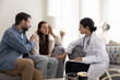 © fizkes - Serious young Indian female doctor telling about healthcare bad problems to couple of patients, talking to stressed shocked woman. Husband giving support to wife, listening to practitioner