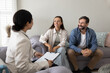 © fizkes - Happy couple of homeowners meeting with insurance agent at home for filling application. Psychologist woman talking to positive husband and wife, writing notes, giving consultation