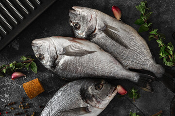 Poster - Top view of fresh raw dorado fish on a wooden cutting board with garlic, pepper, and olive oil. A healthy seafood for cooking food