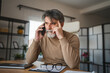 © Miljan Živković - Mature tired man work from home have headache while have phone call