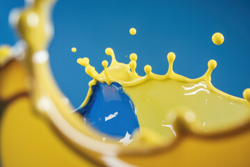 Poster - Dynamic Splashes of Blue and Yellow Paint on a Vibrant Background
