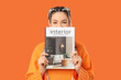 © Pixel-Shot - Beautiful young stylish happy woman with magazine on orange background
