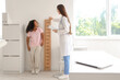 © Pixel-Shot - Female pediatrician with little African-American girl measuring height near stadiometer in clinic