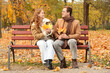 © Pixel-Shot - Beautiful loving young happy couple with fall leaves sitting on bench in autumn park