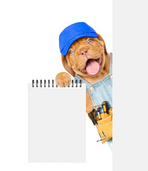 Poster - Happy Mastiff puppy wearing blue cap and denim overalls with tool belt shows empty list from behind blank wahite banner. Isolated on white background