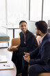 © fizkes - Two multiethnic professionals engaged in conversation, pretty African woman holding drink listening Indian colleague share ideas, solutions, discuss work-related matters met in cozy coworking space