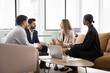 © fizkes - Four multinational young 35s business partners met in modern coworking space, solve joint business, align goals, make strategic decisions, search problem solution collaboratively. Teamwork, briefing