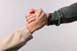 © New Africa - Help and support. People holding hands on light grey background, closeup