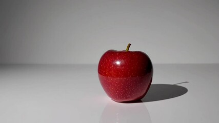 Poster - Red apple with shadow on white surface under bright light, simplicity concept