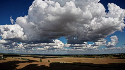 Wall Mural - Dramatic clouds over golden fields under a bright blue sky. Scenic landscape view