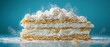 © Gadis - Creamy layered pastry slice dusting over table, blue backdrop