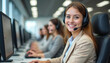 © miss irine - Young woman in headset smiles in call center surrounded by colleagues working at computers. Provides pro customer support, assistance, online help in corporate office. Modern tech workplace, teamwork