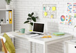© Pixel-Shot - Designer's workplace with blank laptop and color palettes on white brick wall in office