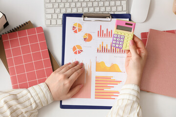 Fototapete - Female accountant with calculator, notebooks, keyboard and financial graphics at table in office