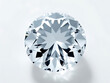 © Nichapa888 - A diamond solitaire in focus, with light playing off its surfaces, placed in a minimalistic