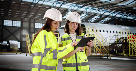 Fototapete - Woman with tablet checks aircraft engine at airport maintenance hangar