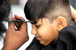 © Mrudang - Boy is getting his haircut done at salon. Barber is cutting hair of a 4 year old cute little boy at barber shop. little child is enjoying his new hair style and hair cut. Boy is looking very smart.