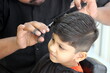 © Mrudang - Boy is getting his haircut done at salon. Barber is cutting hair of a 4 year old cute little boy at barber shop. little child is enjoying his new hair style and hair cut. Boy is looking very smart.